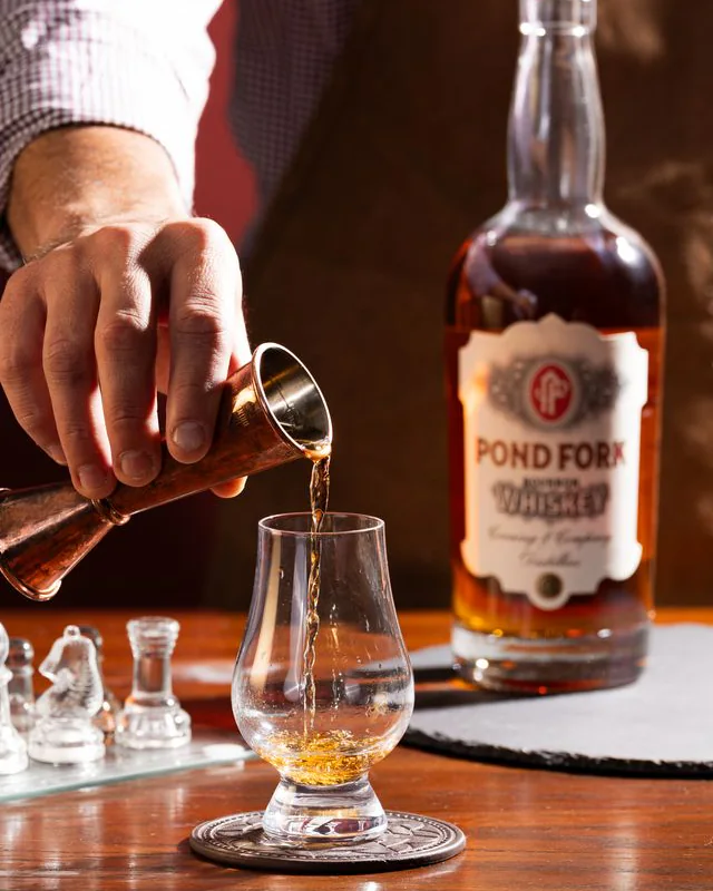 Pouring POND FORK Bourbon from a copper jigger into a tasting glass